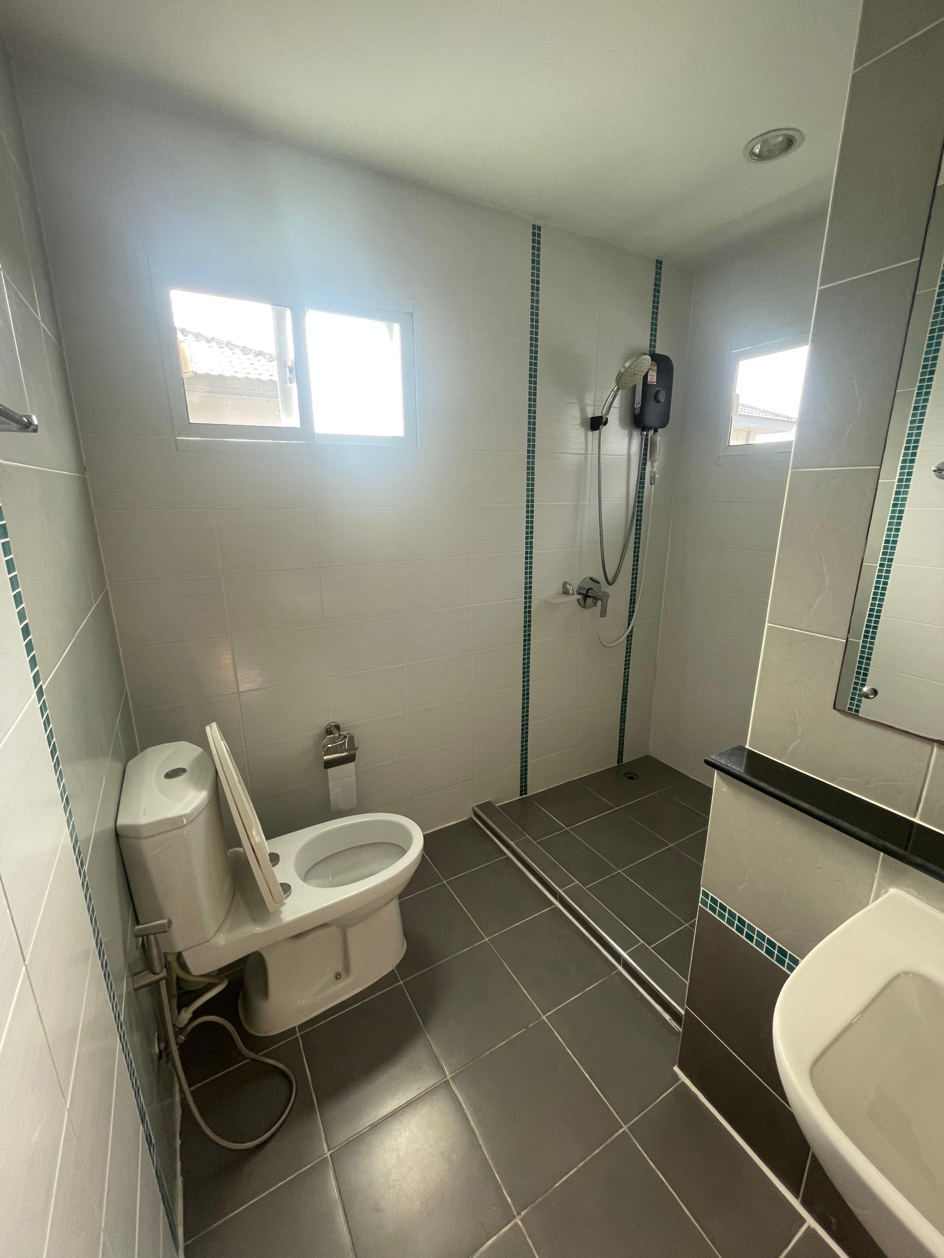 Modern, spacious bathroom with toilet, shower, and sink in a Thalang house for rent, pet-friendly.