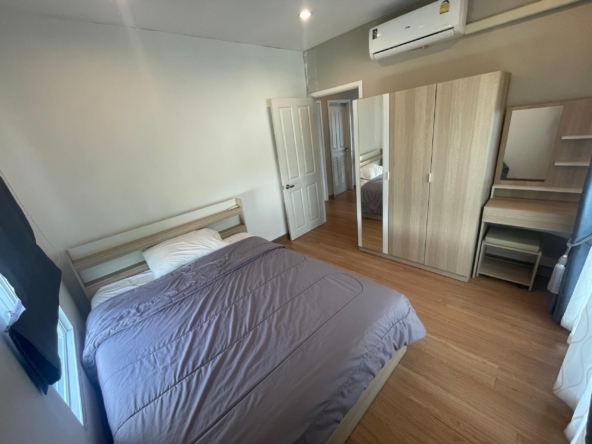 Spacious bedroom in a Thalang house, features bed, wooden wardrobe, dressing table, AC.