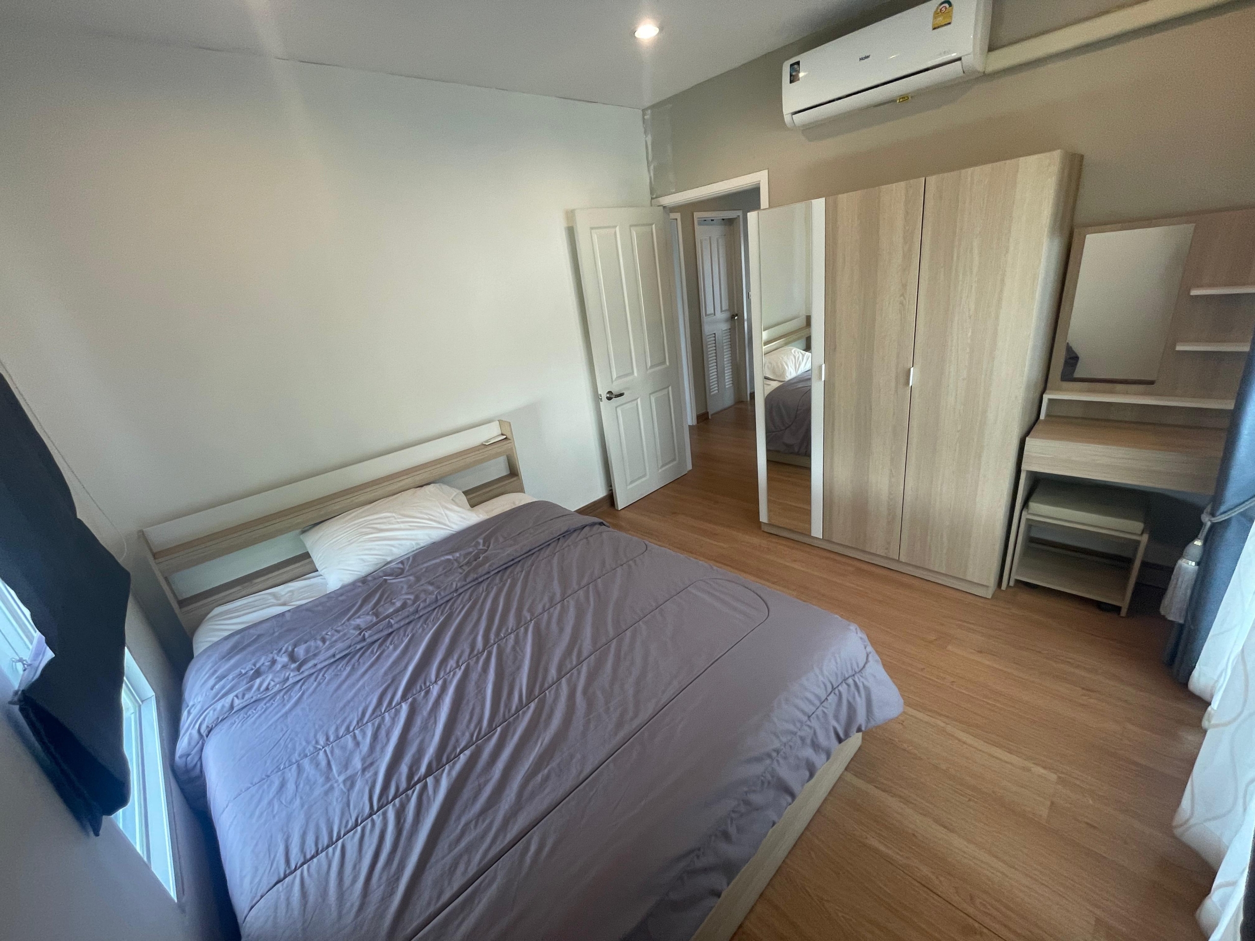 Spacious bedroom in a Thalang house, features bed, wooden wardrobe, dressing table, AC.