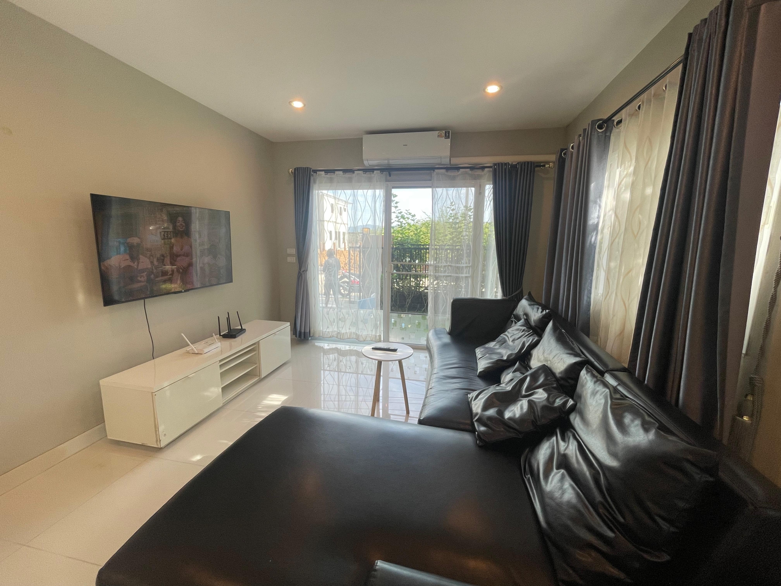Spacious living room in a pet-friendly Thalang house for rent, with sofa and garden view.