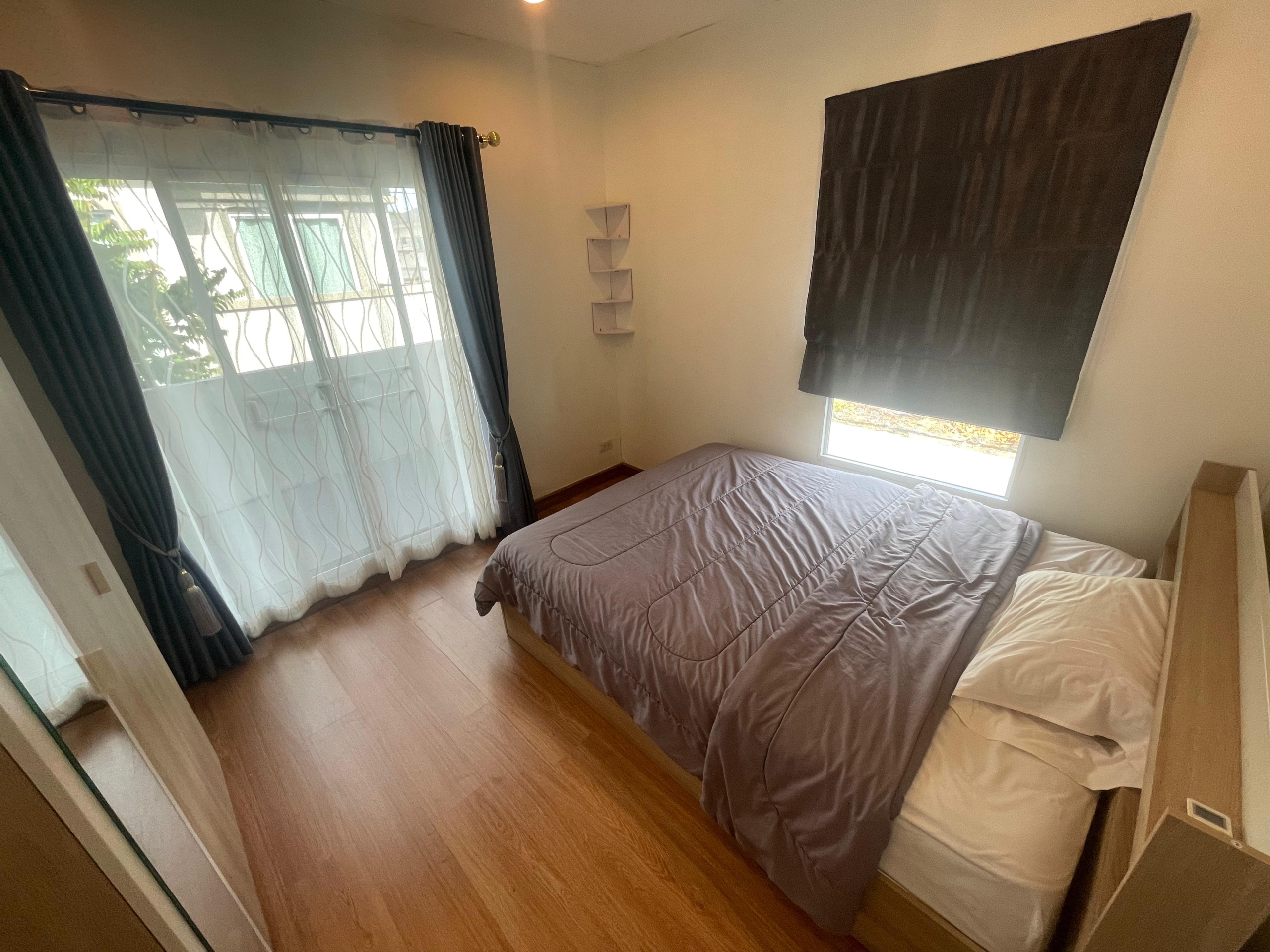 Spacious bedroom in a Thalang house for rent with wooden floor and large windows.